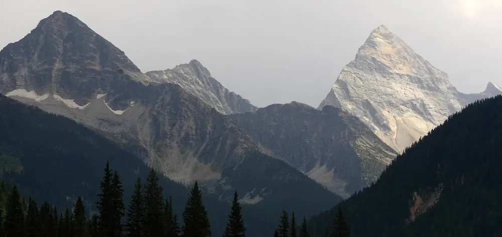 Berge im Glacier-Nationalpark bei Rogers Pass, rechts der spitze Mount Sir Donald über dunklem Nadelwald