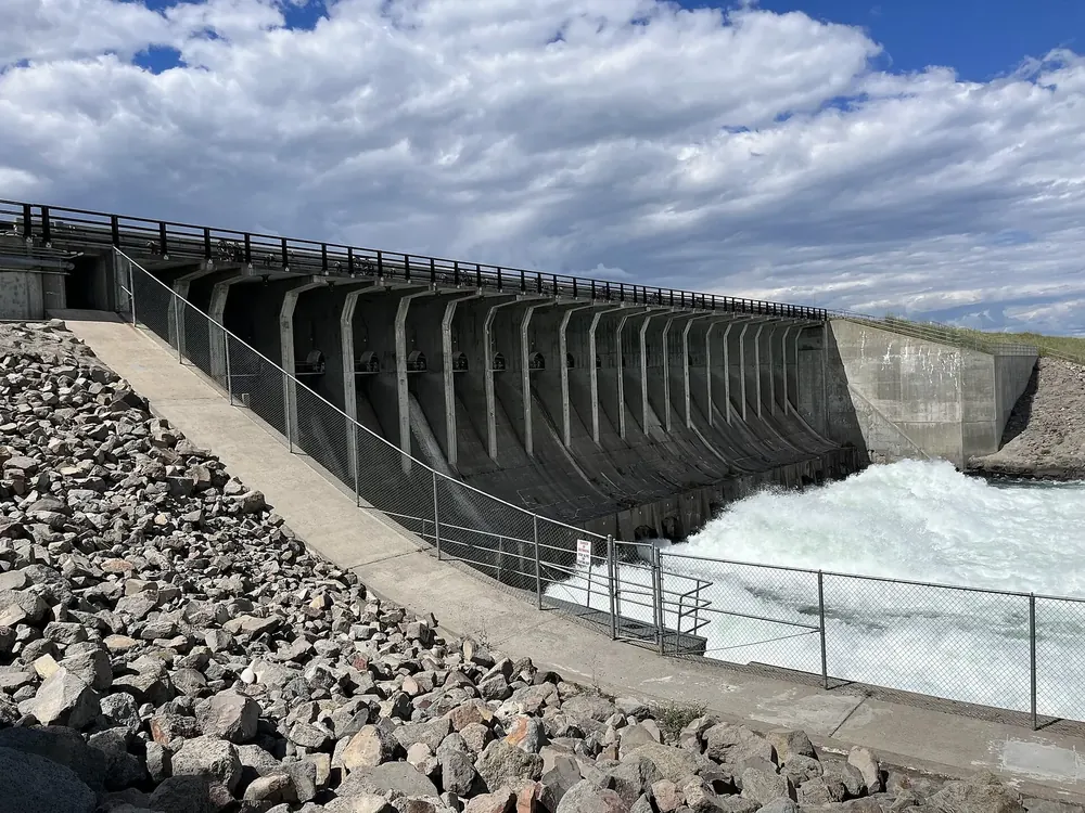 Jackson Lake Dam von der Seite: Betonstaumauer mit Pfeilern, unten schäumendes Wasser und Steinschüttung