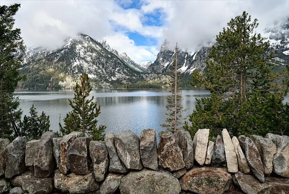 Jenny Lake Overlook: Natursteinmauer vor dem See, dahinter Nadelbäume und der Eingang des Cascade Canyon