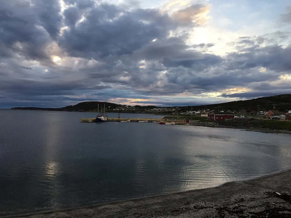 Morgendämmerung über der Bucht von Rocky Harbour, am Ufer Häuser und ein Anleger unter Wolken
