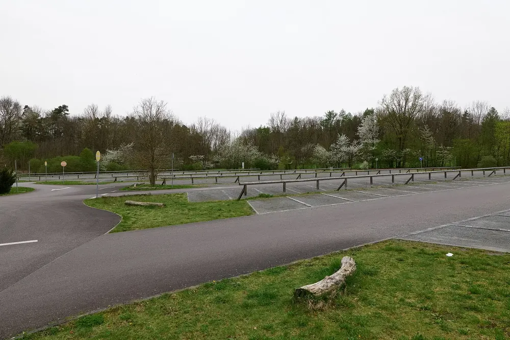 Parkplatz an der Thiemsburg im Nationalpark Hainich: asphaltierte Stellflächen mit Holzgeländern, dahinter Laubwald