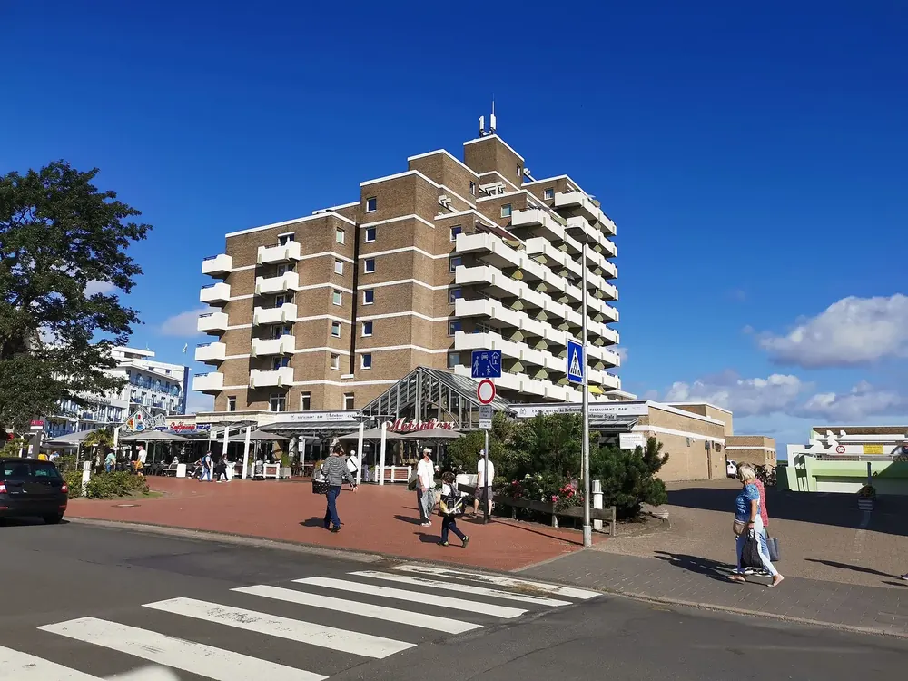 Cuxhaven-Duhnen: Hotelhochhaus und Kurmittelhaus an einem Platz mit Zebrastreifen unter blauem Himmel
