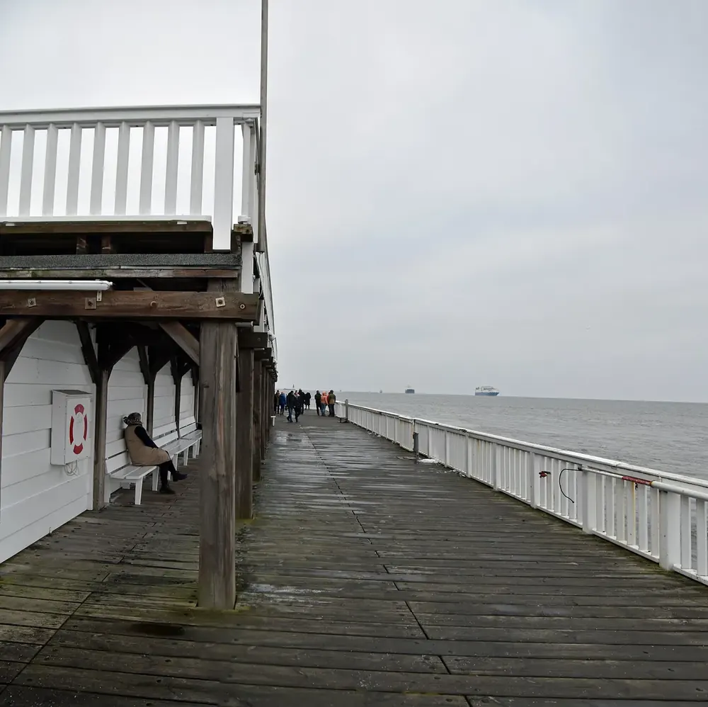 Die Alte Liebe in Cuxhaven: hölzerne Aussichtsplattform am Elbufer mit Geländer und Spaziergängern