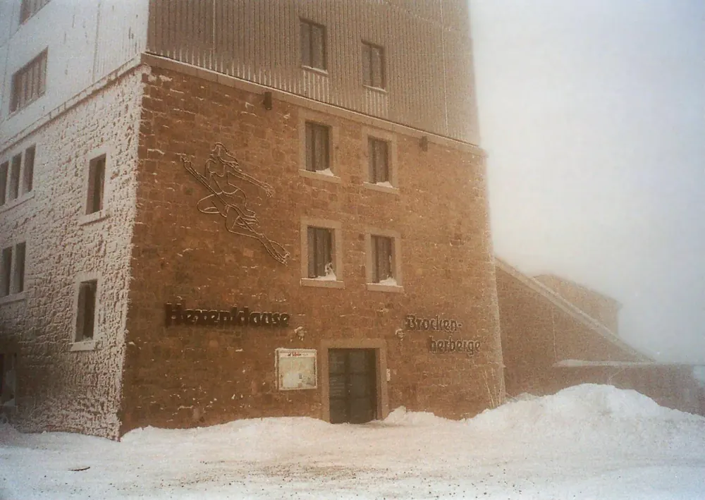 Turmfuß der Brockenherberge mit der Hexenklause im Winternebel, Raureif an der Steinfassade und Schnee davor