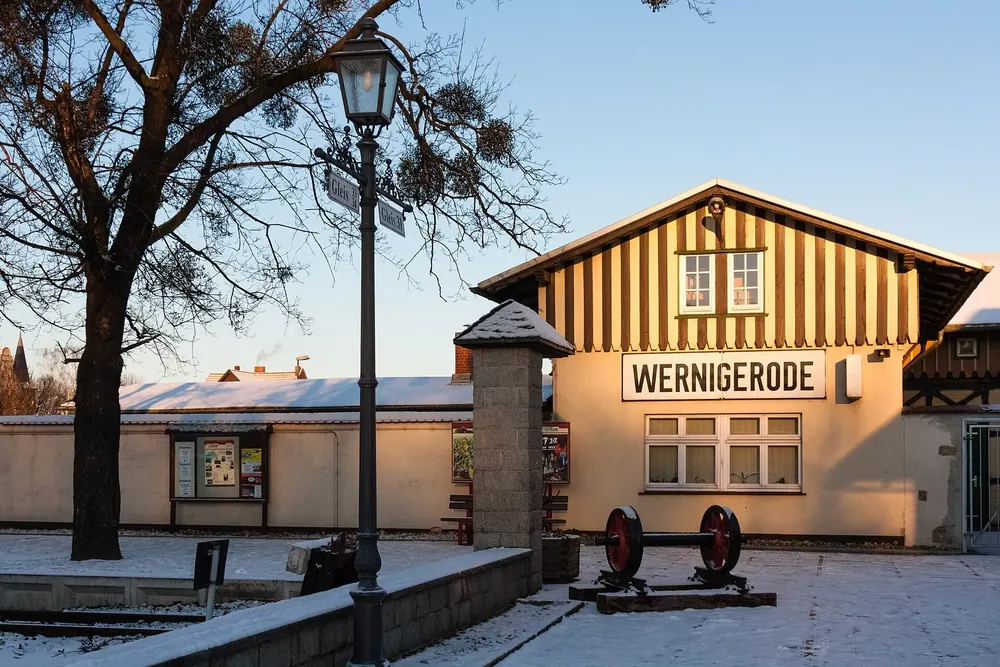 Bahnhof Wernigerode der Harzer Schmalspurbahnen: Fachwerkgebäude mit Schriftzug Wernigerode im Abendlicht, davor Laterne