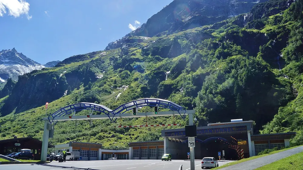 Nordportal des Felbertauerntunnels im Amertal: Tunneleinfahrt mit Bogenkonstruktion vor steilen grünen Berghängen