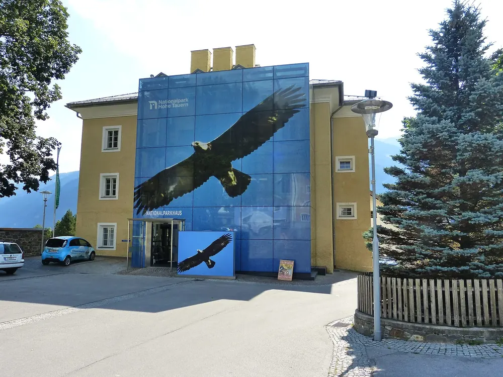 Nationalparkhaus Matrei in Osttirol: historisches Schulhaus mit blauer Glasfassade und aufgedrucktem Steinadler