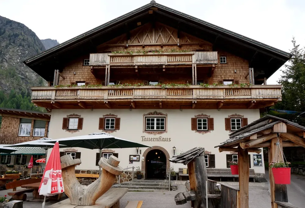 Matreier Tauernhaus: alpiner Gasthof mit Holzbalkonen und Schindelgiebel, davor Terrasse mit Sonnenschirmen