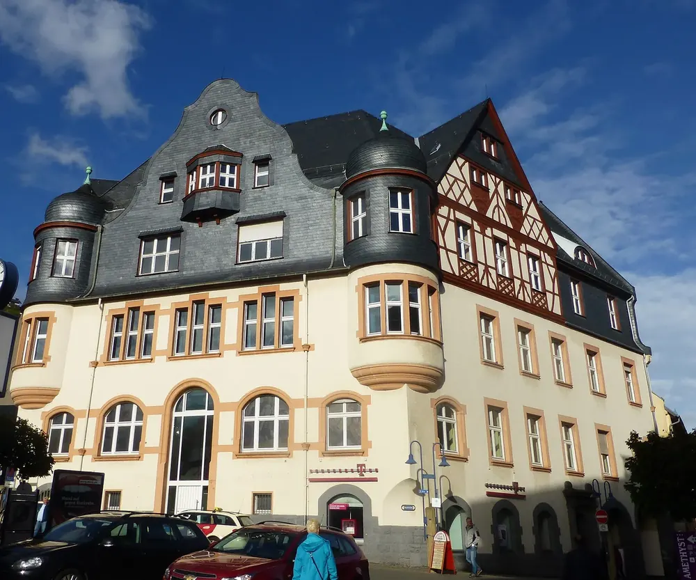 Repräsentatives Eckgebäude mit Schieferdach, Erkertürmchen und Fachwerkgiebel in Idar-Oberstein unter blauem Himmel