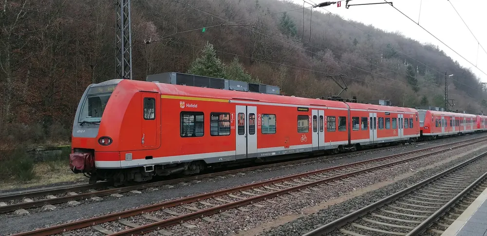 Roter Regionaltriebwagen im Bahnhof Türkismühle, dahinter ein bewaldeter Hang
