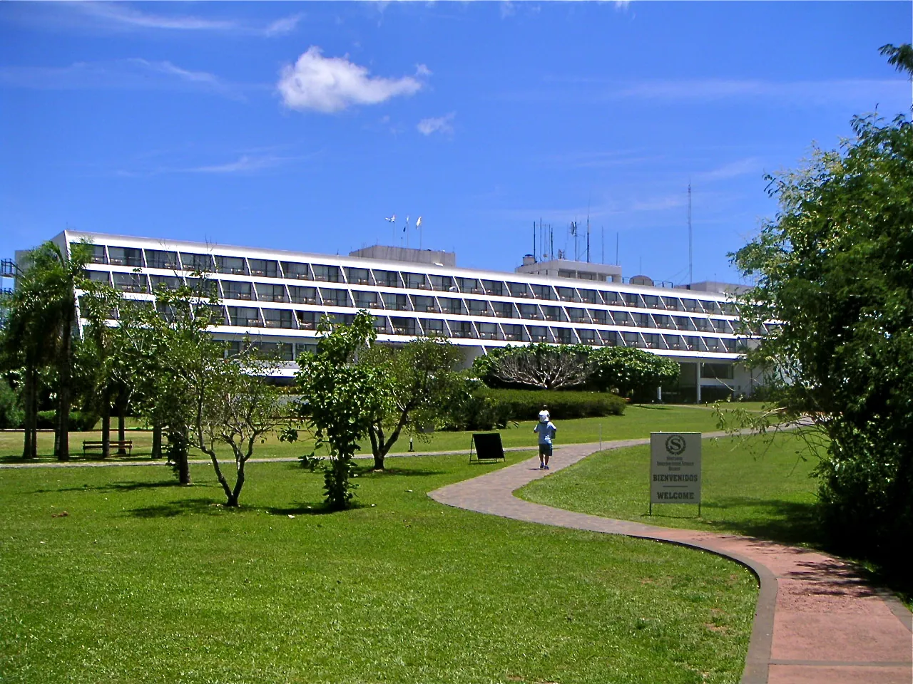 Das langgestreckte Hotelgebäude des heutigen Gran Meliá Iguazú im Iguazú-Nationalpark hinter einer Rasenfläche mit Bäumen und geschwungenem Weg