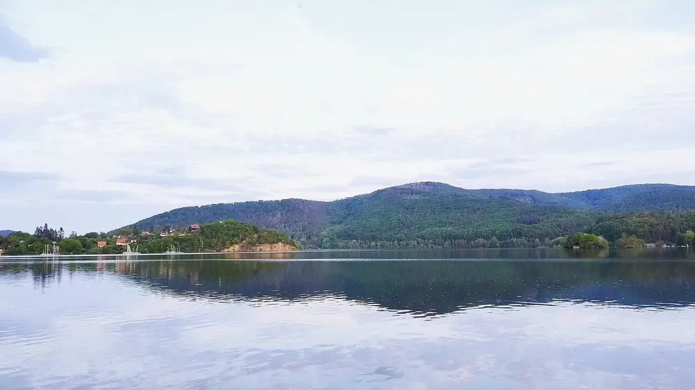 Edersee bei Bringhausen im Frühling: ruhige Wasserfläche mit Spiegelung, dahinter bewaldete Kellerwaldhöhen