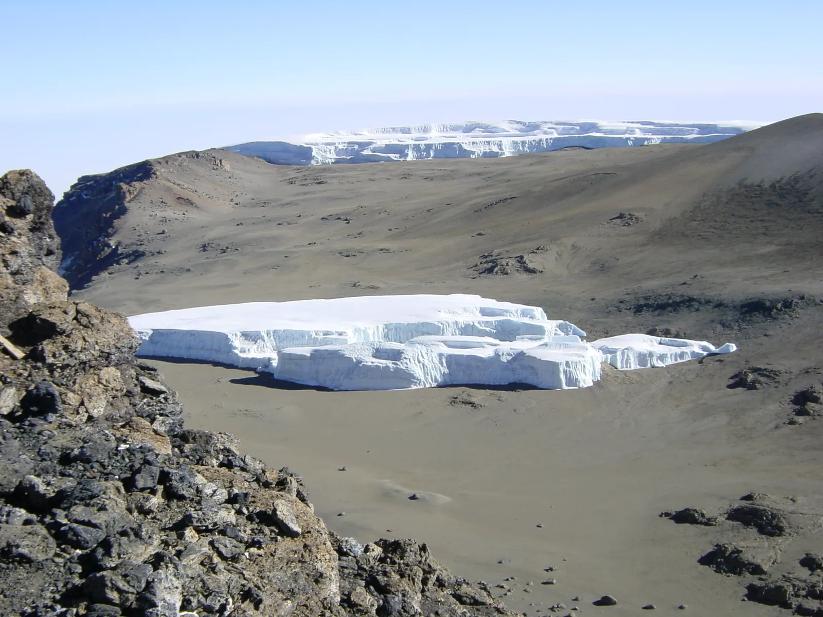 Der Furtwängler-Gletscher als flacher Eisblock mit senkrechten Wänden im Kibo-Krater des Kilimandscharo-Nationalparks, dahinter das Nördliche Eisfeld