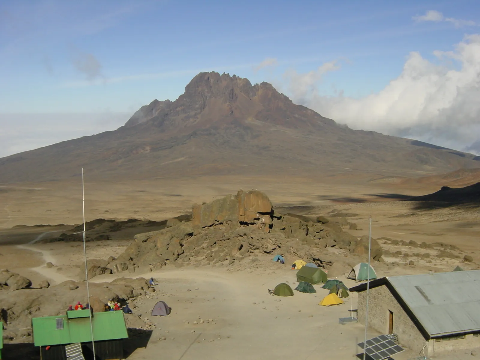Blick von den Kibo Huts im Kilimandscharo-Nationalpark über die Hochwüste des Sattels zum zackigen Mawenzi, vorn Hüttendächer und Zelte
