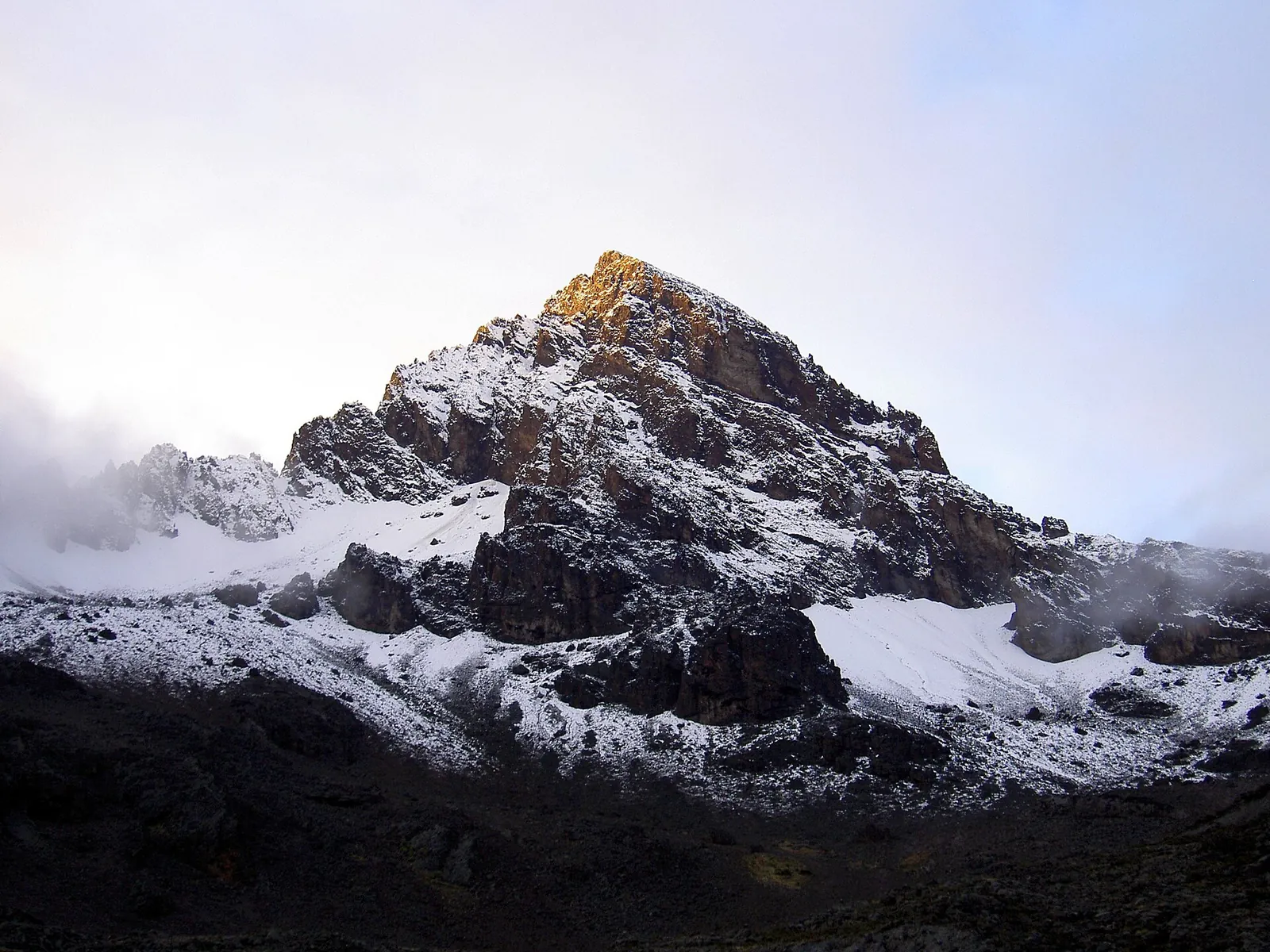 Die zerklüfteten Felsgipfel des Mawenzi im Kilimandscharo-Nationalpark mit frischem Schnee, die höchste Spitze im ersten Sonnenlicht