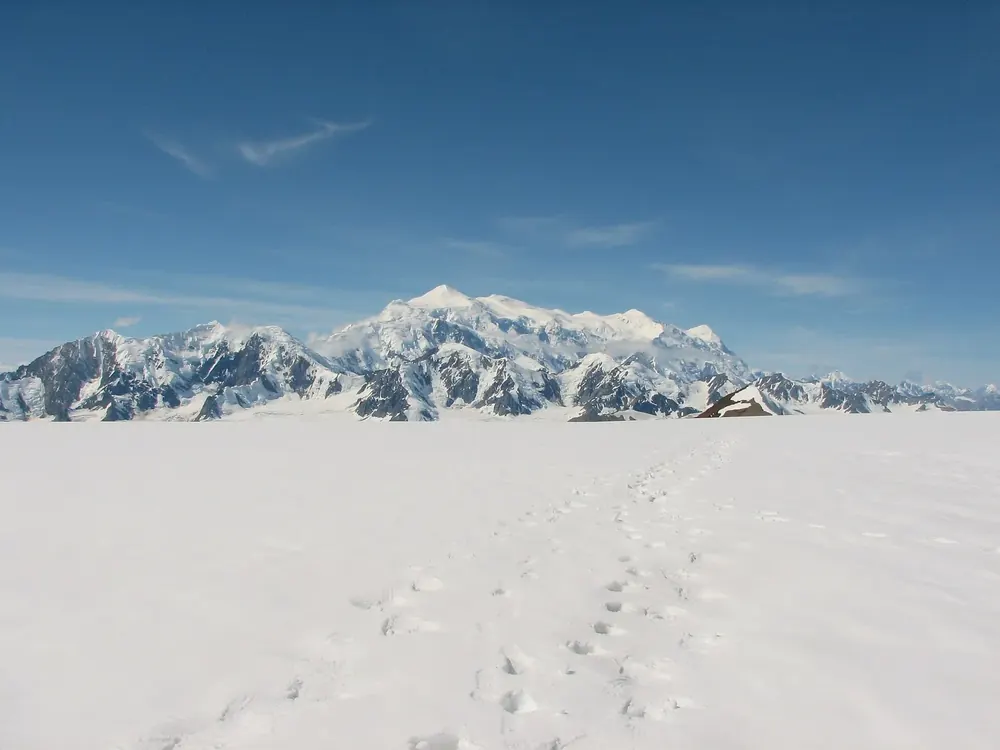 Mount Logan von Nordosten: vergletscherter Gebirgsstock über dem weiten Kluane-Eisfeld mit Fußspuren im Schnee
