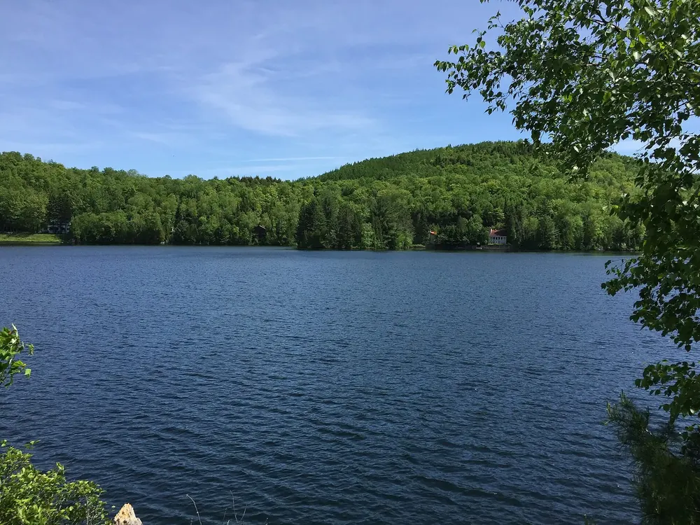Blick von der Shewenegan-Brücke nach Süden über den Lac Wapizagonke mit bewaldeten Ufern unter blauem Himmel