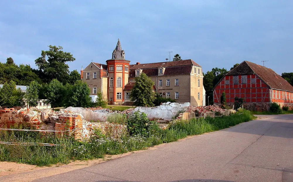 Schloss Ankershagen, einstige Schliemann-Schule: Backsteinbau mit Turm neben einer roten Scheune an einer Dorfstraße