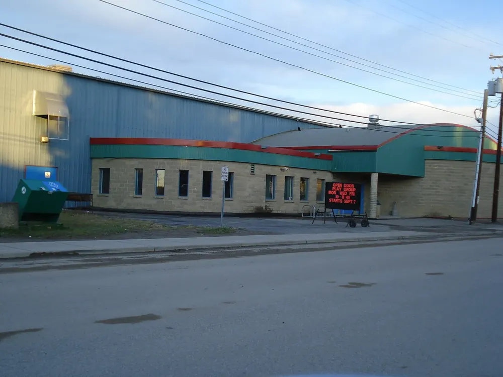Freizeitzentrum in Fort Simpson: flacher Bau mit roter und grüner Dachkante an einer breiten Straße