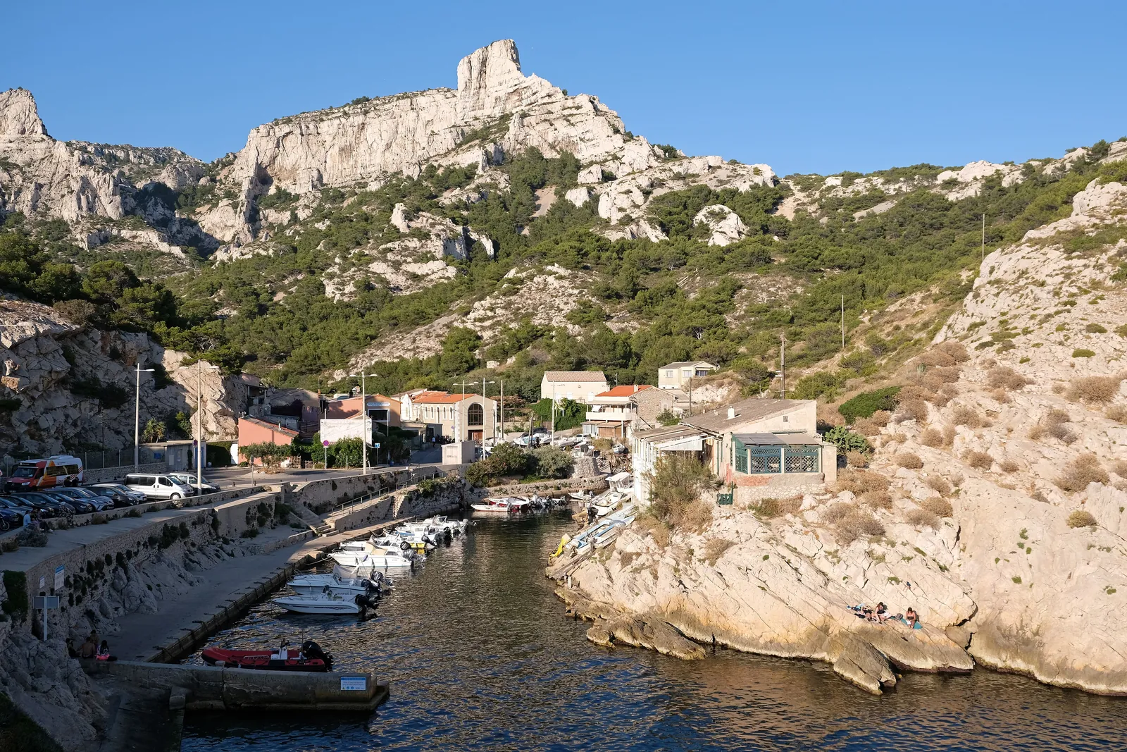 Der kleine Hafen von Callelongue am Westende des Nationalparks Calanques: Boote vor Häusern, darüber helle Kalkfelsen