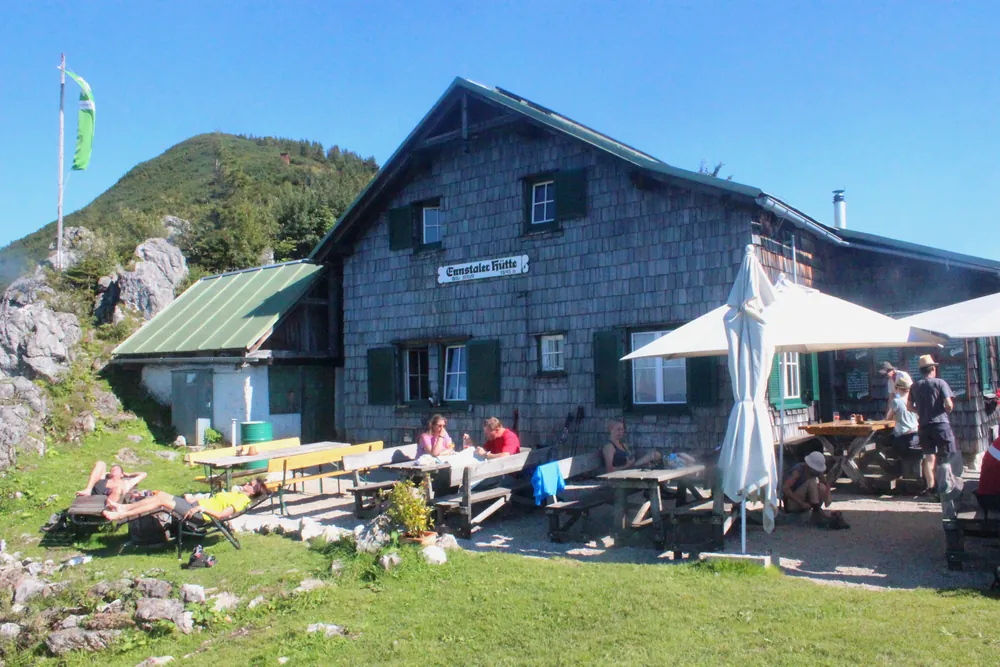 Die Ennstaler Hütte an der Grenze des Nationalparks Gesäuse, ein Holzhaus auf einer Bergwiese zwischen Wald und Felsgipfeln