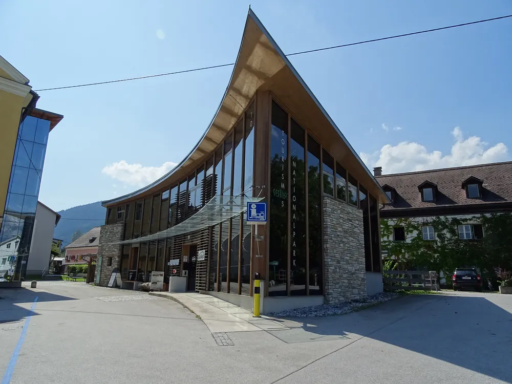 Das Infobüro des Nationalparks Gesäuse in Admont, ein moderner Glasbau mit geschwungenem Dach an einer Straßenecke
