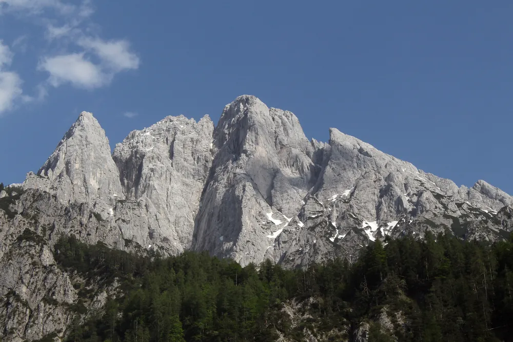 Die hellen Kalkzacken des Großen Ödsteins im Nationalpark Gesäuse über dunklem Bergwald, gesehen aus dem Johnsbachtal