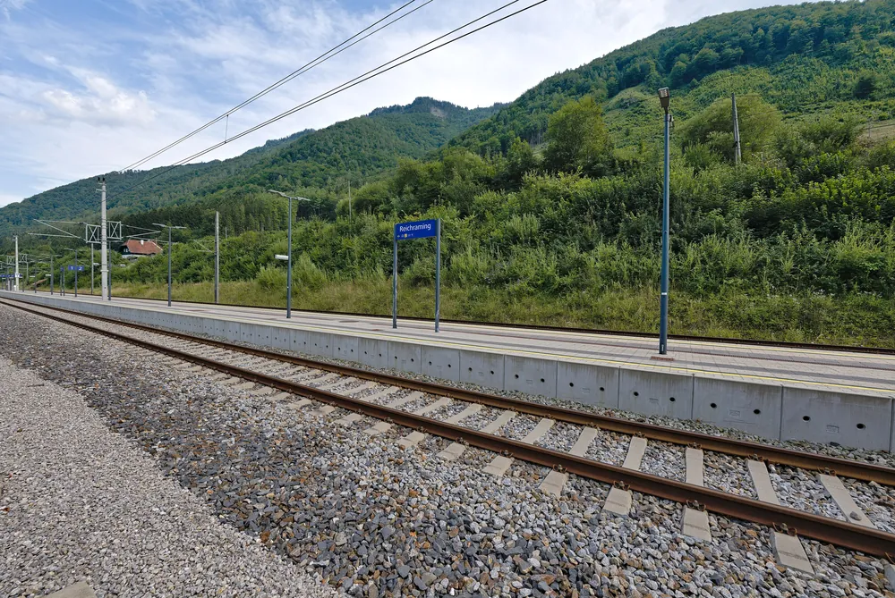 Bahnsteig des Bahnhofs Reichraming im Ennstal, Ausgangspunkt für den Nationalpark Kalkalpen, vor bewaldeten Hängen