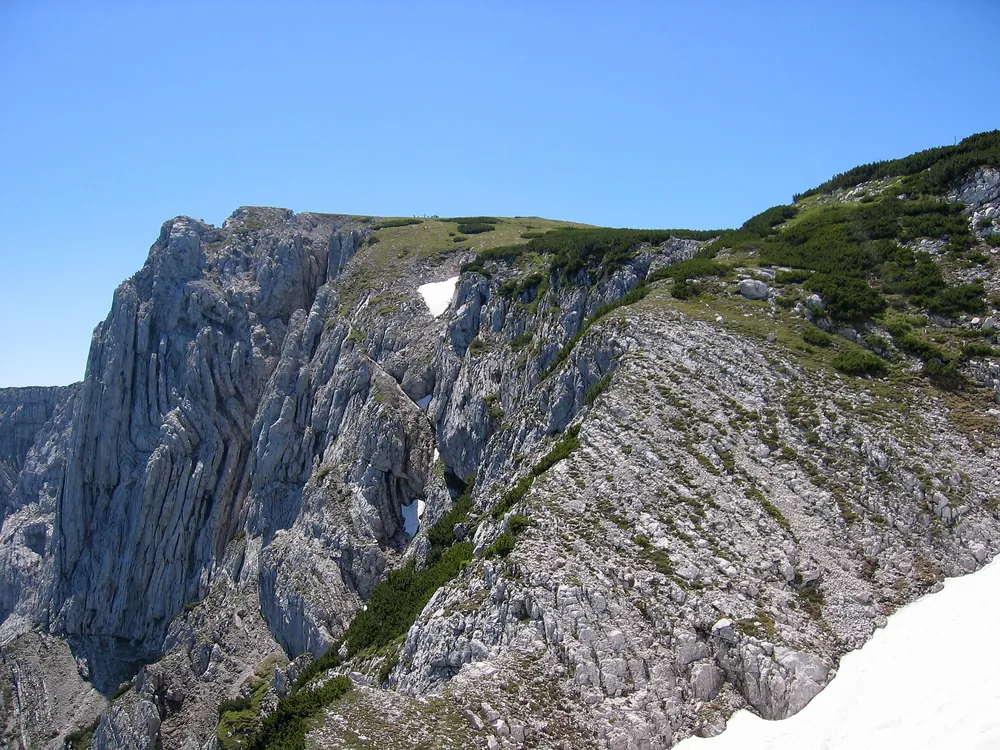 Der Hohe Nock mit dem Nockpfeiler im Nationalpark Kalkalpen: helle, zerklüftete Kalkwände mit Schneeresten im Sengsengebirge