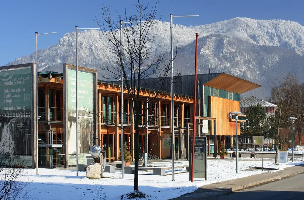 Das Nationalpark Zentrum Molln, Sitz der Verwaltung des Nationalpark Kalkalpen, mit Holzfassade vor verschneiten Bergen
