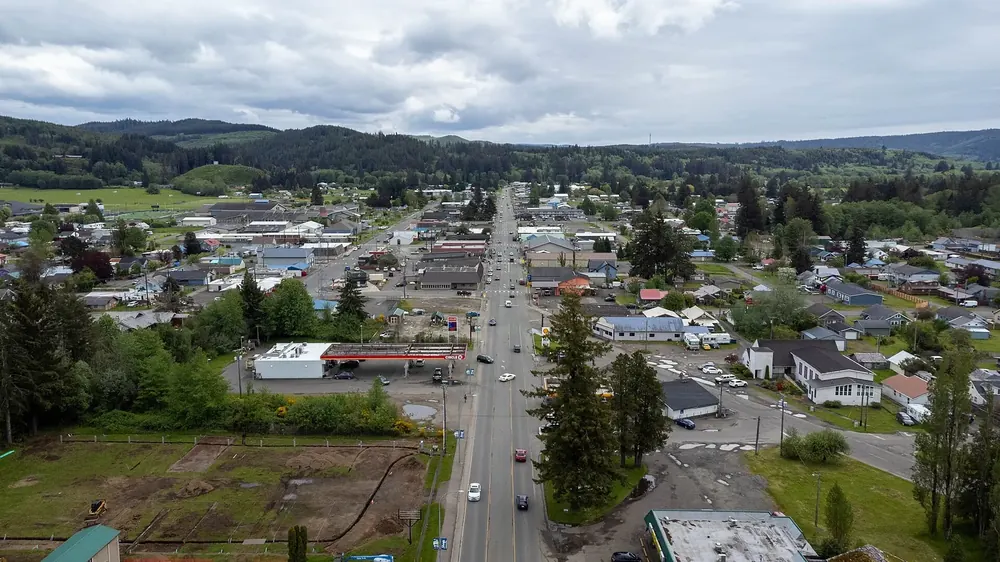 Luftaufnahme von Downtown Forks: Hauptstraße mit Geschäften und Häusern, umgeben von Wald und Hügeln