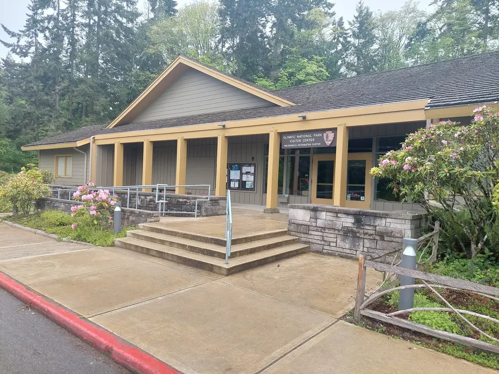 Olympic National Park Visitor Center in Port Angeles: flacher Bau mit Säulenvorbau, Treppe und blühenden Rhododendren