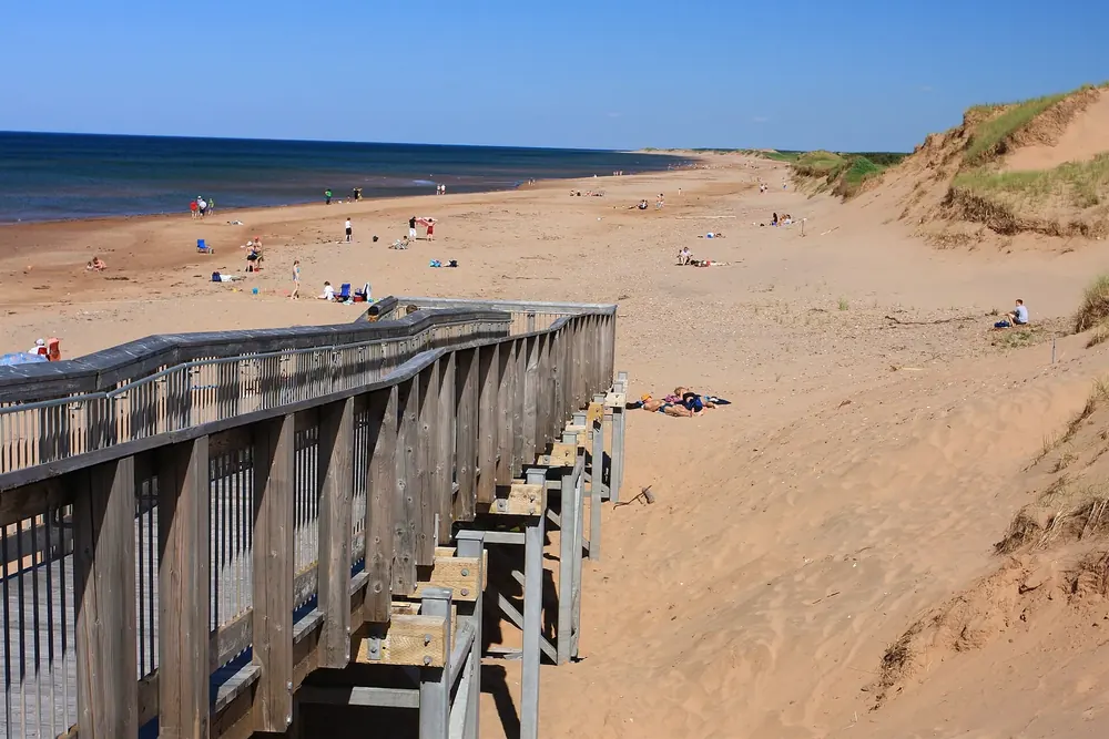 Brackley Beach: Holzsteg über die Dünen hinab zum weiten Sandstrand mit Badegästen am Meer