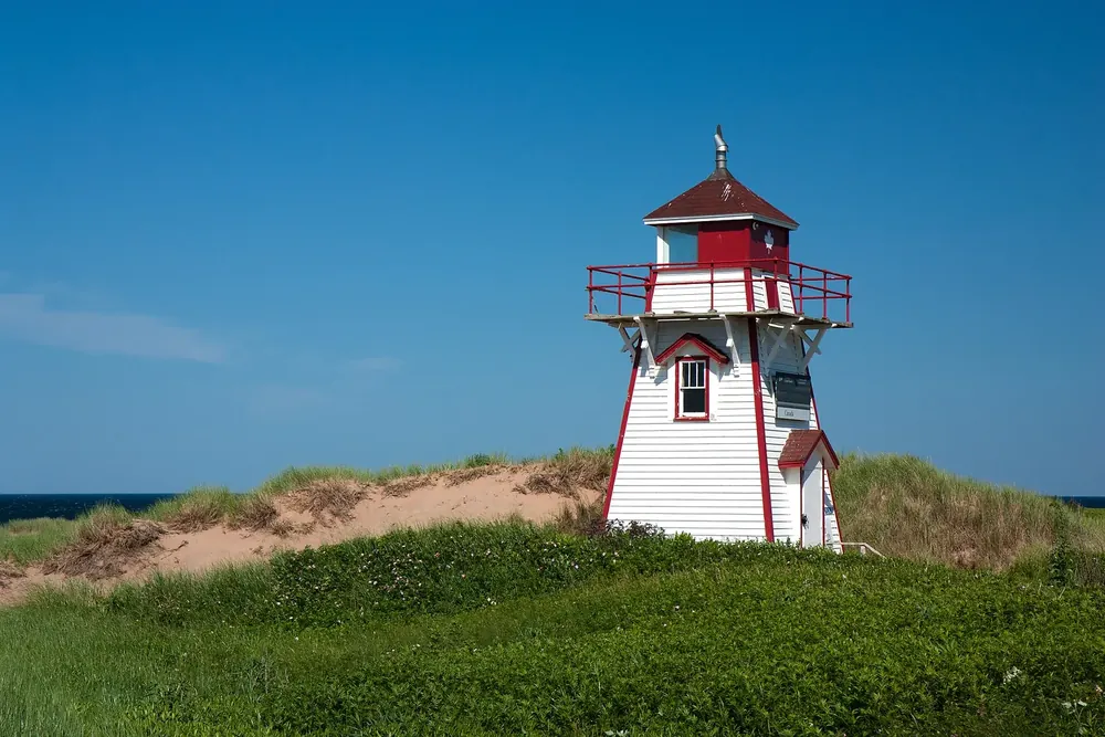 Leuchtturm Covehead: weiß-roter Holzleuchtturm auf einer grünen Düne vor tiefblauem Himmel