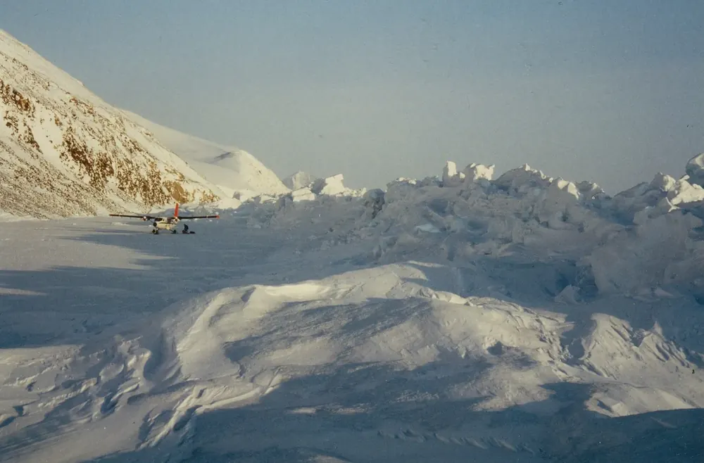 Aufgeworfenes Meereis am Cape Columbia im April, dahinter verschneite Hänge und ein kleines Flugzeug