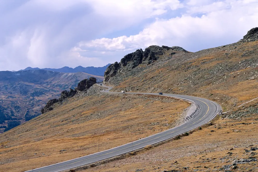 Rock Cut an der Trail Ridge Road: Straßenkurve durch alpine Tundra, daneben Felstürme und Blick auf Bergketten