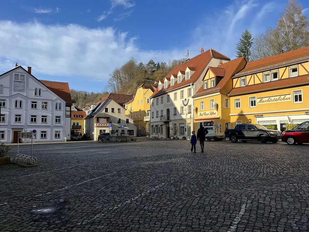 Marktplatz von Stadt Wehlen: Kopfsteinpflaster vor bunten Bürgerhäusern und Fachwerk unter blauem Himmel