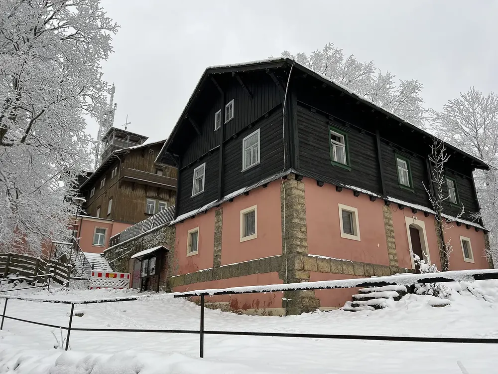 Gipfel des Großen Winterbergs im Winter: ehemalige Berggaststätte mit dunkler Holzfassade zwischen bereiften Bäumen