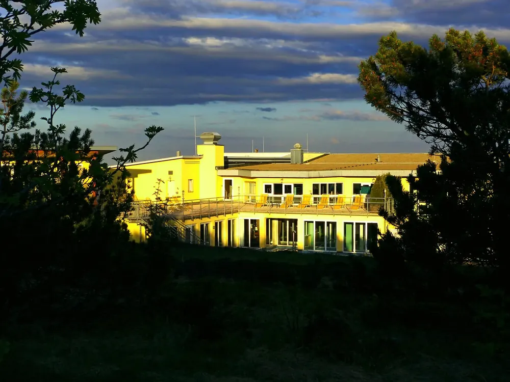 Hotel Schliffkopf an der Schwarzwaldhochstraße im Abendlicht, eingerahmt von Bäumen unter dunklen Wolken