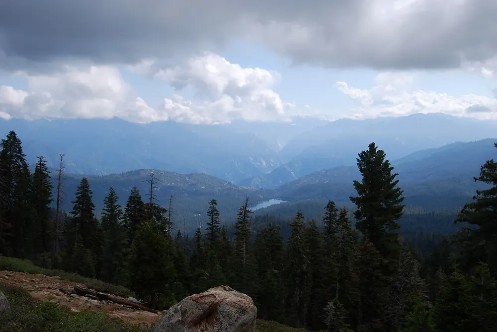 Blick vom Panoramic Point über bewaldete Bergrücken und Täler, in der Tiefe der Hume Lake unter Wolken