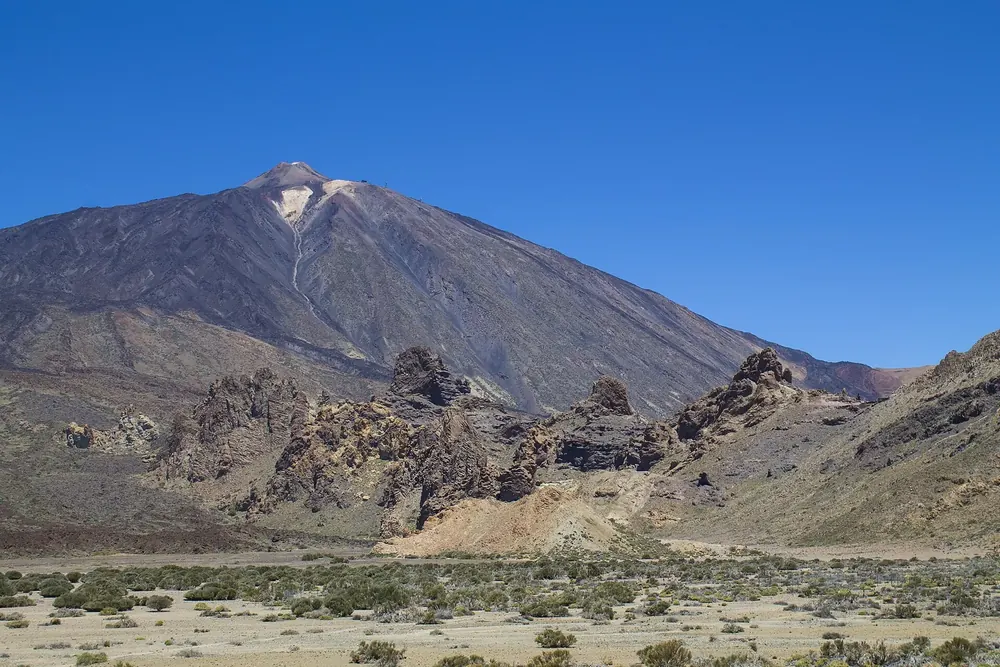 Pico del Teide und Montaña Blanca über der kargen Hochebene von Las Cañadas unter tiefblauem Himmel