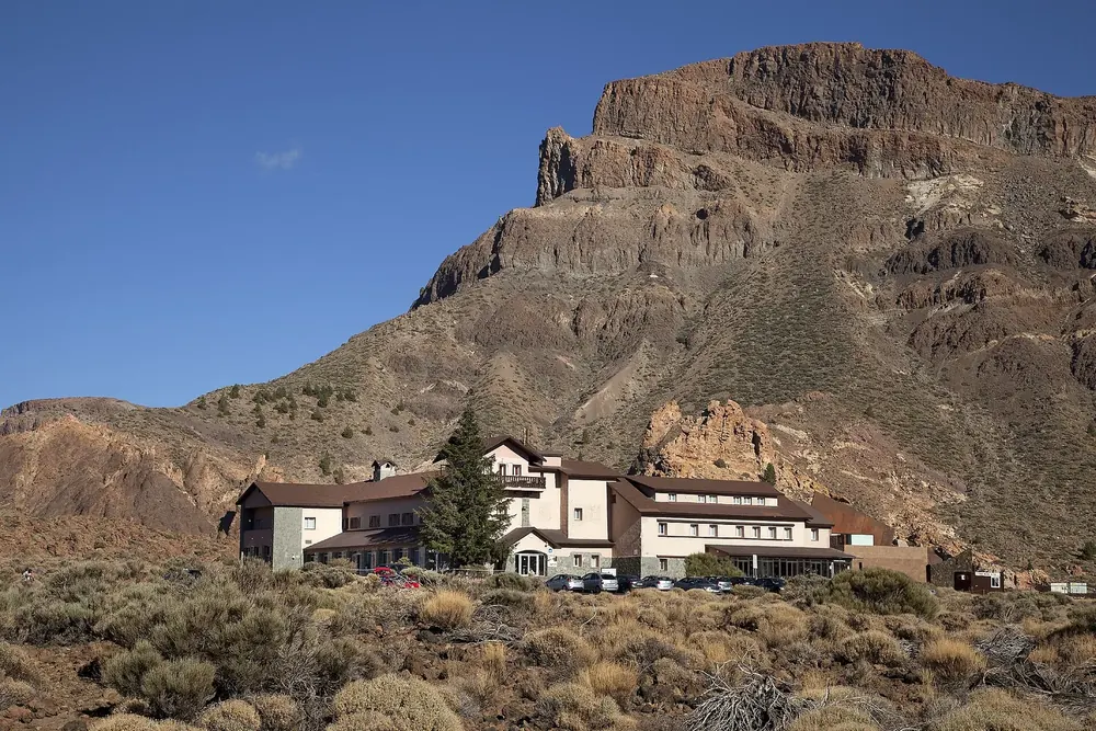 Parador de Las Cañadas del Teide: Hotelgebäude am Fuß der schroffen Felswände des Alto de Guajara