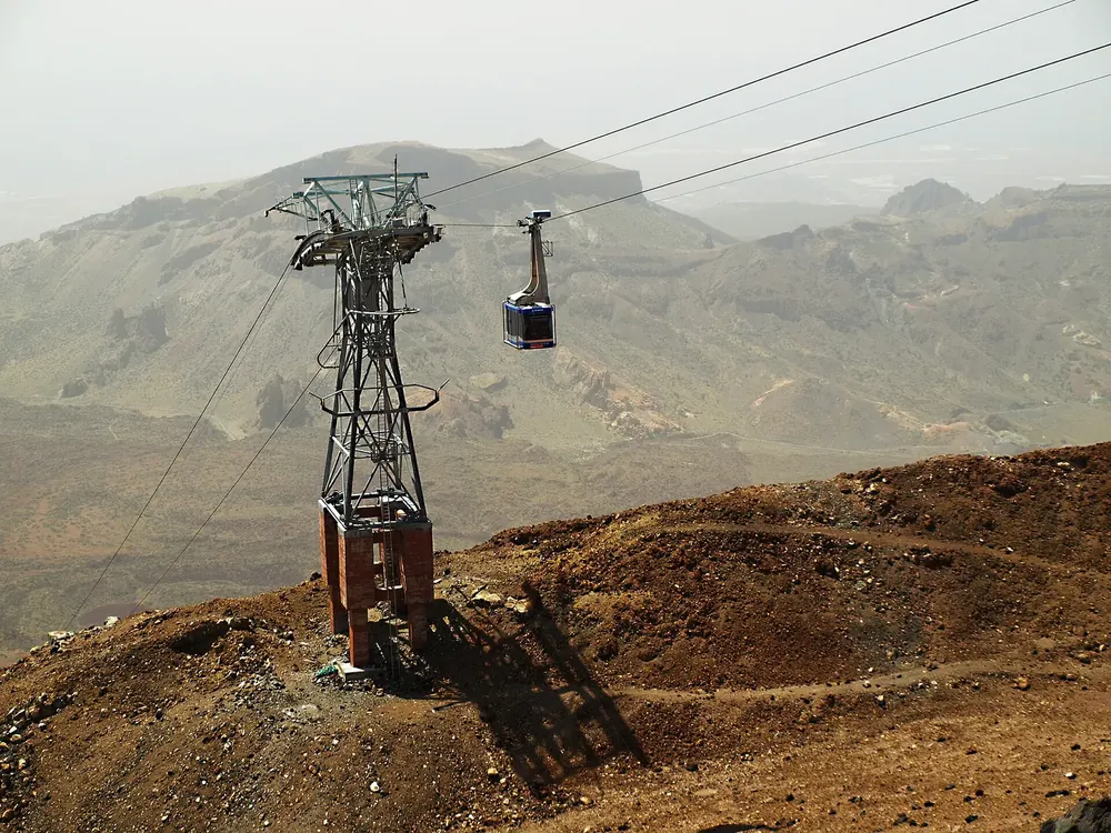 Teide-Seilbahn nahe der Talstation: Stahlmast und Kabine über der rotbraunen Vulkanlandschaft