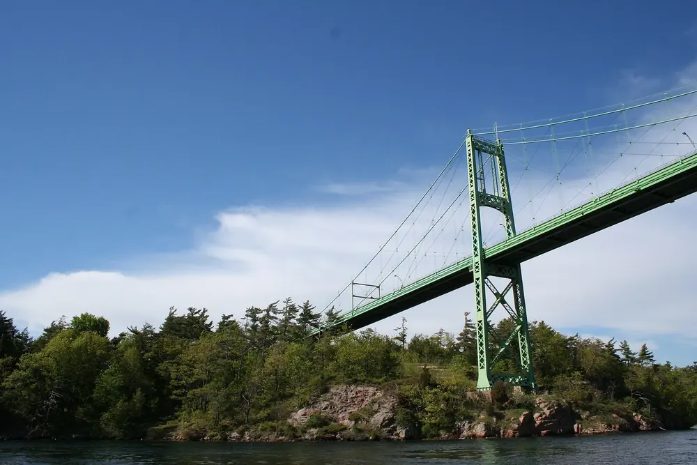 Hängebrücke der Thousand Islands Bridge über einem Seitenarm zur bewaldeten, felsigen Hill Island