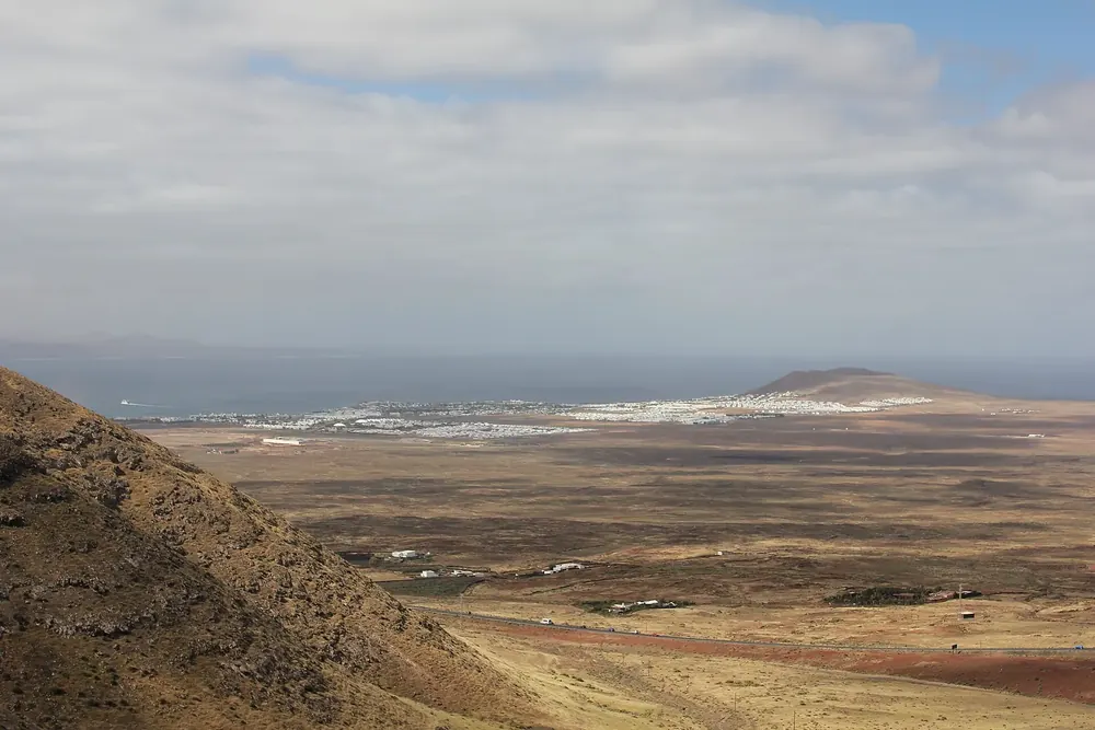 Fernblick von den Hängen bei Femés über die karge Ebene auf Playa Blanca und das Meer
