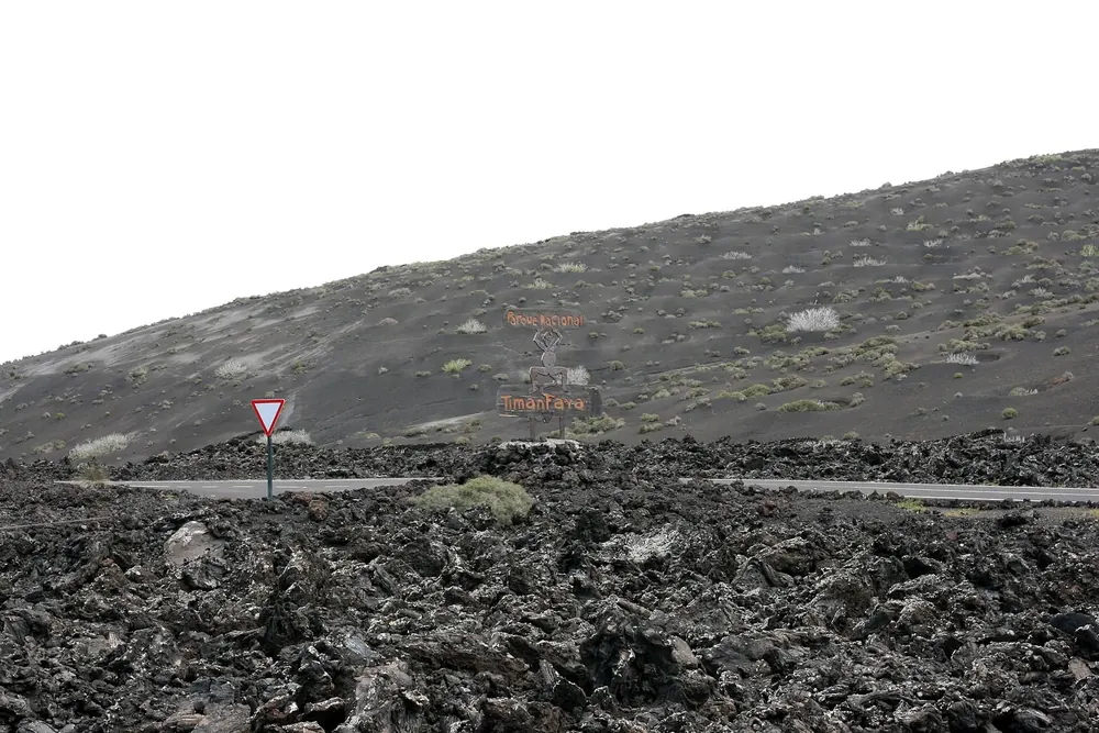 Lavafeld am Tinguatón an der LZ-67: schwarze, zerklüftete Lavabrocken vor einem kahlen Vulkanhang