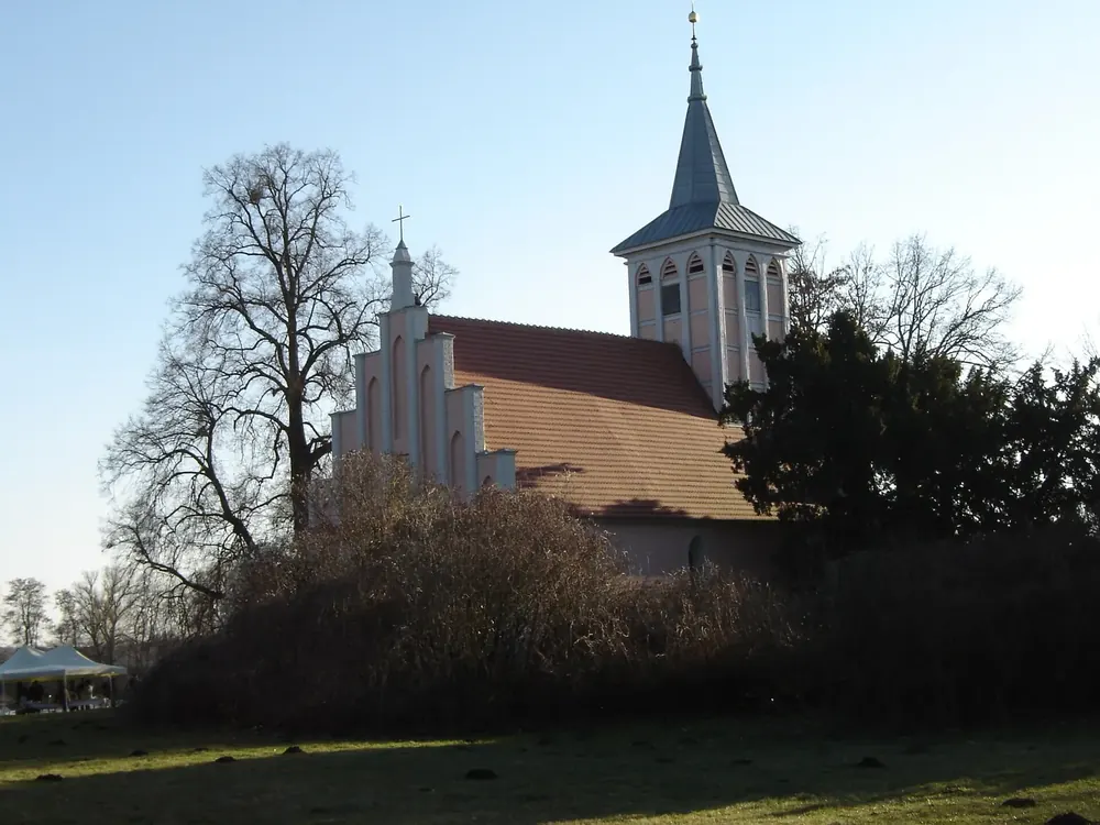 Dorfkirche Criewen: Backsteinkirche mit weißem Staffelgiebel und hellem Turm zwischen kahlen Bäumen