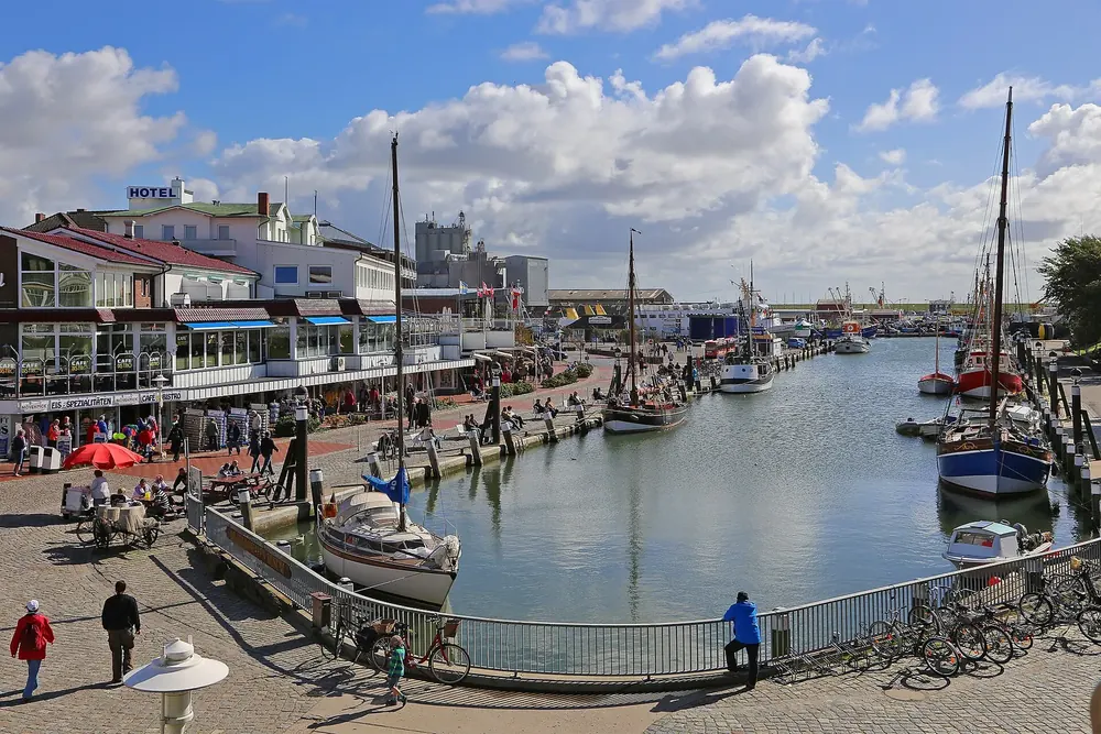 Museumshafen in Büsum: Segelschiffe im Hafenbecken, am Kai Restaurants, Spaziergänger und Hotels