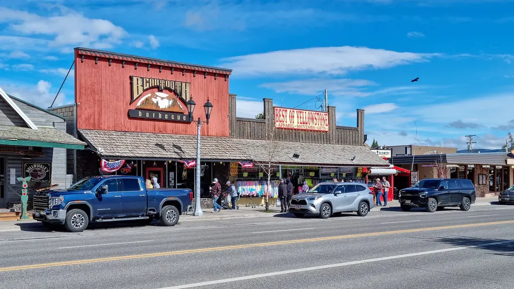 Canyon Street in West Yellowstone: Geschäfte mit Westernfassaden, davor Pick-ups unter tiefblauem Himmel