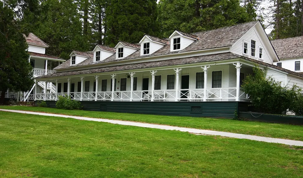 Wawona Hotel: weißes Holzgebäude mit umlaufender Veranda und Gauben vor gepflegtem Rasen und Bäumen